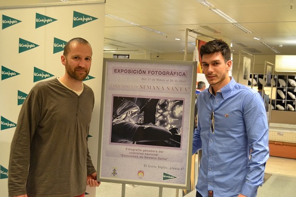 El ganador del primer premio del concurso y el protagonista de la fotografía posan junto al cartel de la exposición, que recoge la imagen ganadora.